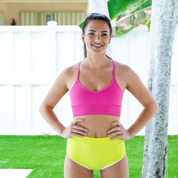 Alice Visby, de cabelos escuros, tendo aula de pilates hardcore com seu treinador